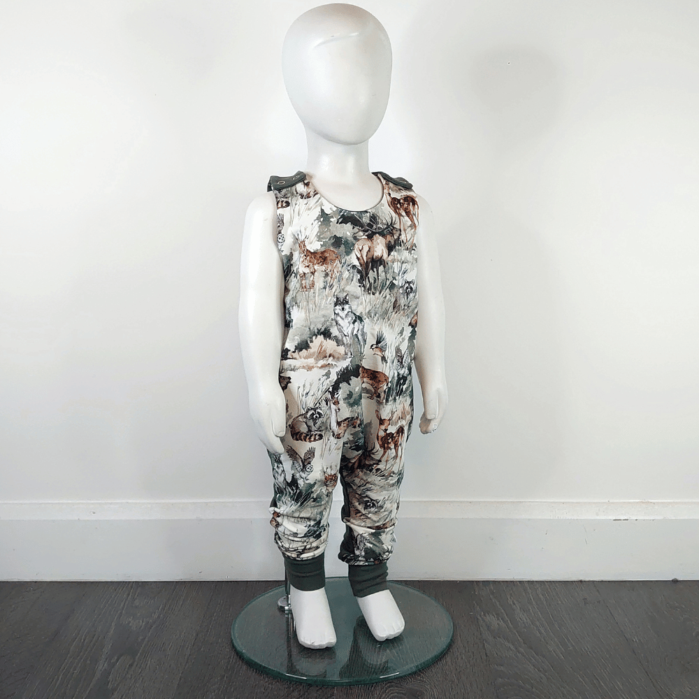 Mannequin wearing Baby romper - dungarees style with shoulder snap buttons and mountain forest animals print