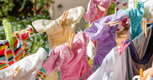 Colorful cloth diapers are drying on a clothesline in the sun.